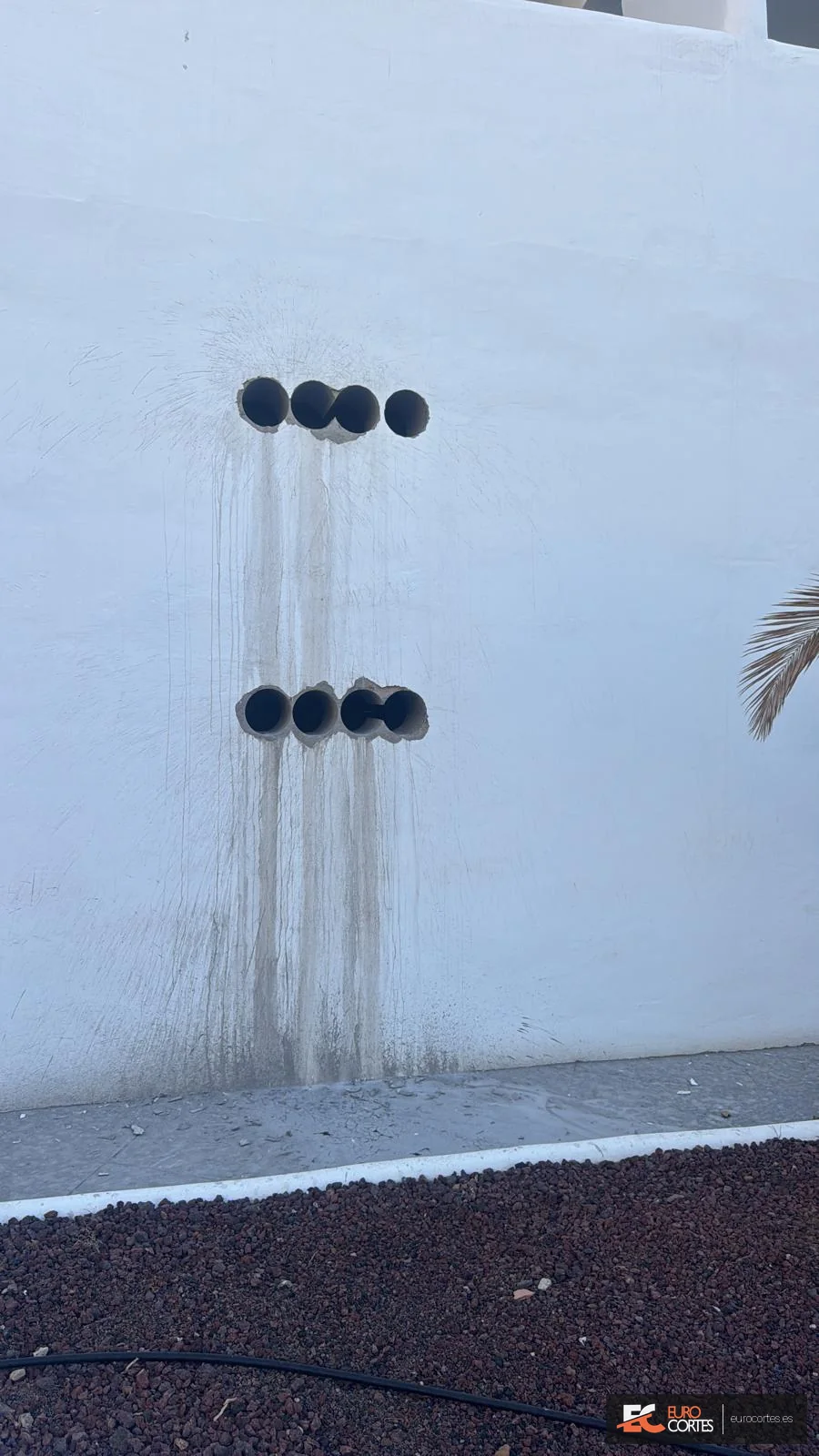 Dos filas de perforaciones circulares ejecutadas en un muro exterior.