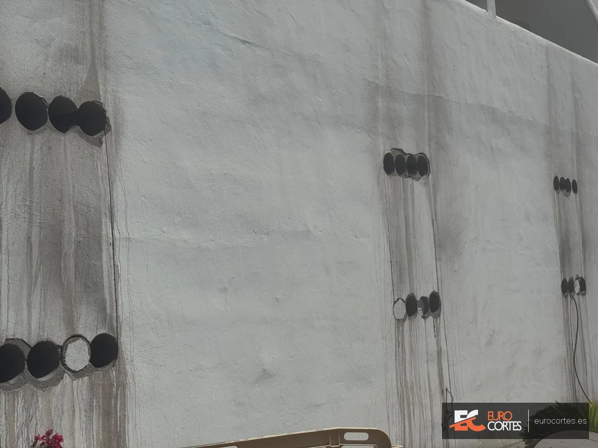 Vista cercana de varias perforaciones alineadas en un muro de hormigón.